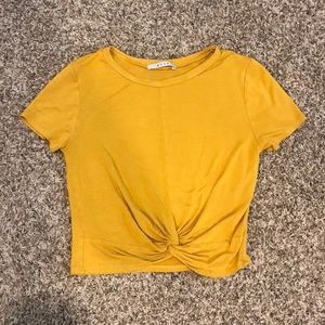 a yellow-mustard crop top with a tie in front.